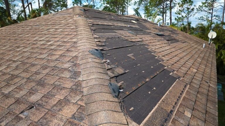A roof with a visibly damaged shingle and signs of roof wear. The broken or missing shingle exposes the underlayment, indicating potential leaks and the need for repair or replacement. The damage highlights common roofing issues caused by weather or aging.