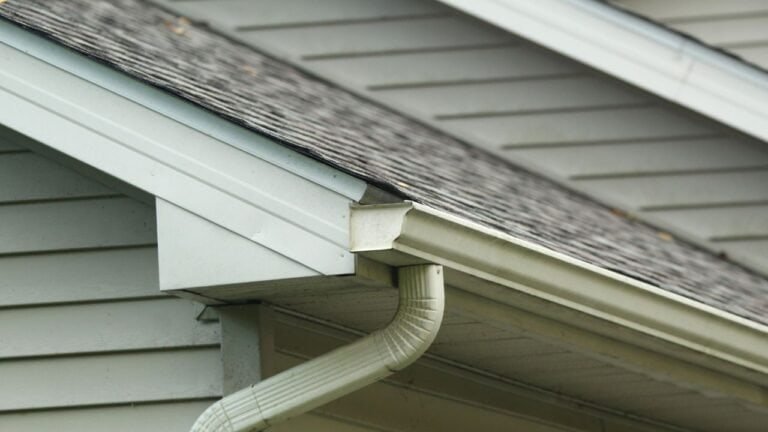 A close-up view of a house gutter attached along the roofline. The image highlights the gutter’s material, design, and placement, showing how it channels rainwater away from the home’s roof and foundation. Details such as seams, edges, or potential debris may be visible.