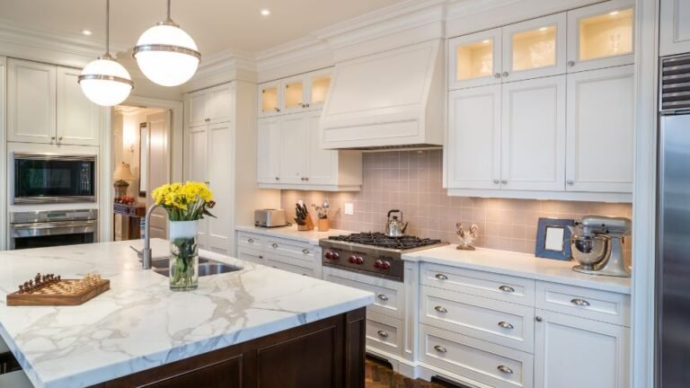 A kitchen with marble counter tops and white cabinets.
