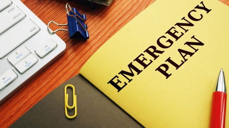 An emergency plan document placed on a desk alongside a pen and a notebook. The layout suggests preparedness and organization, with the emergency plan serving as a guide for safety procedures or crisis response. The pen and notebook indicate readiness for notes or updates.