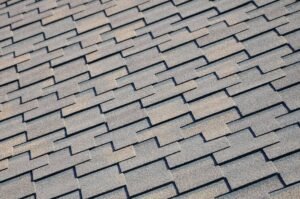 A close-up view of a roof with gray asphalt shingles. The textured shingle surface highlights durability and weather resistance, showing the layered design that helps protect the home from rain and other outdoor elements.