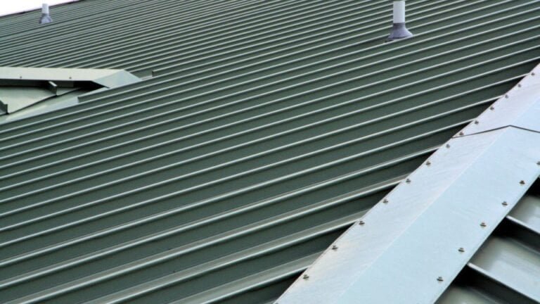 A close-up view of a metal roof with overlapping metal roofing panels. The smooth, reflective surface showcases the strength, durability, and weather-resistant qualities of the material. The interlocking design highlights modern roofing construction.
