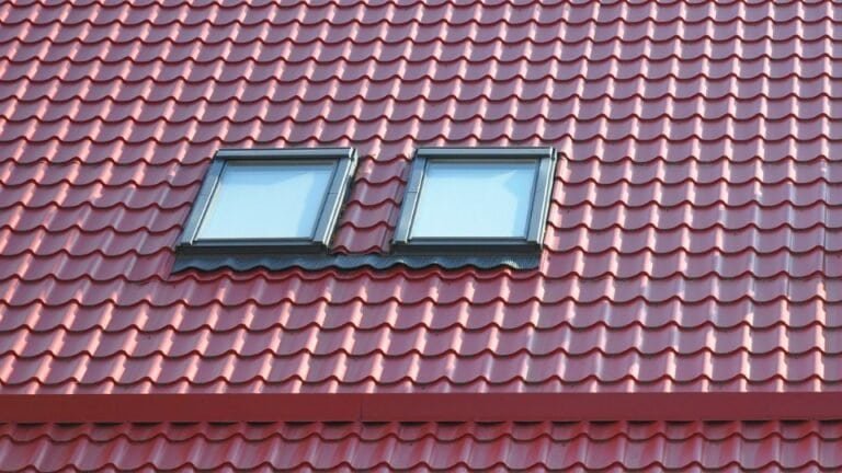 A red roof with two windows built into it, likely dormer or skylight-style windows. The roof features a neat, uniform design with visible tiles, adding character and contrast to the house’s architecture. The windows provide natural light to the upper floor or attic space.