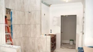 A bathroom featuring a shower and tile flooring. The tiles are neatly arranged, complementing the overall design of the space. The shower may include glass doors or a curtain, and the bathroom is clean and well-lit, emphasizing a modern and functional layout.