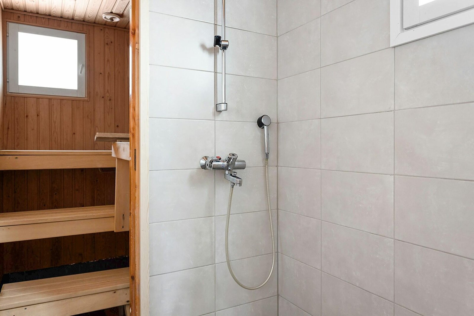 A bathroom featuring white tiled walls and floors, accented with black and white fixtures or decorative elements. The space may include a sink, toilet, and shower or bathtub, with lighting that highlights the clean, modern, and stylish design.