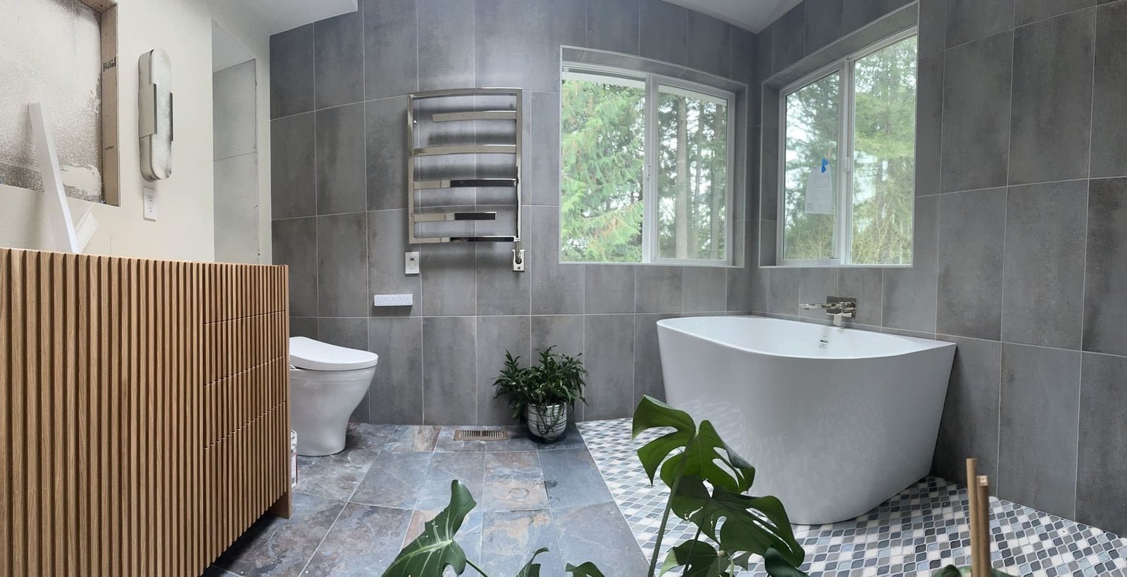 A bathroom featuring a large bathtub and a sink with a countertop and mirror. The space has tiled or painted walls and flooring, with lighting that highlights the clean and organized layout. The design emphasizes comfort and functionality for daily use.