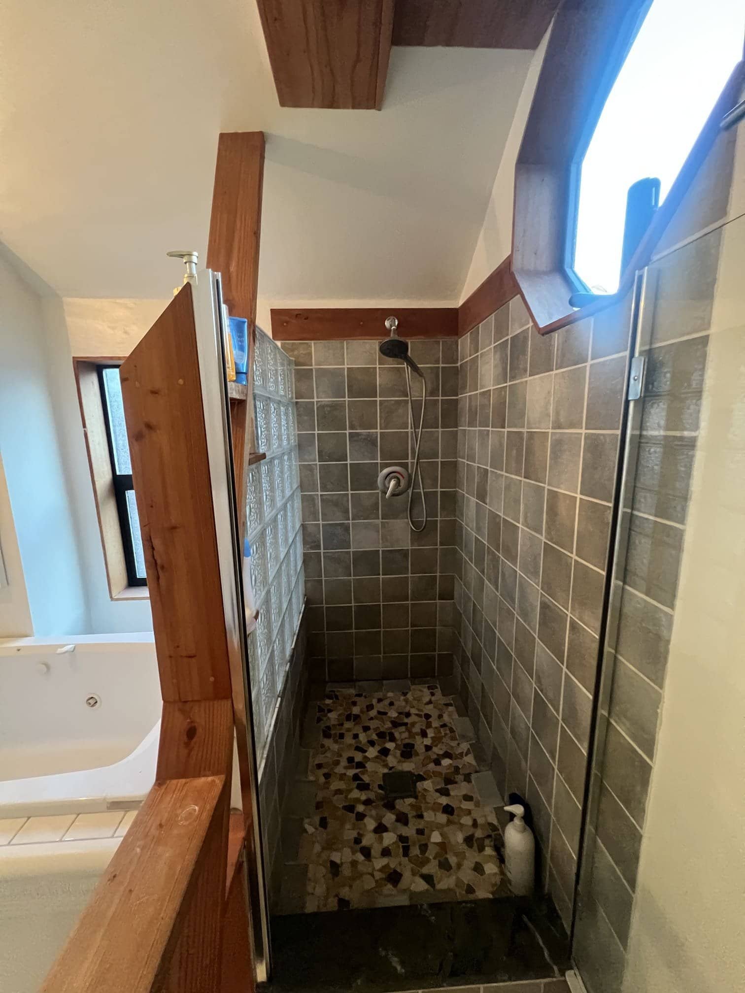 A bathroom featuring a bathtub combined with a shower, either with glass doors or a shower curtain. The walls and floor are tiled or painted, and the space may include a sink and toilet. The layout is clean, functional, and designed for comfortable daily use.
