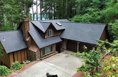 A spacious modern house with dark roofing and surrounding greenery.