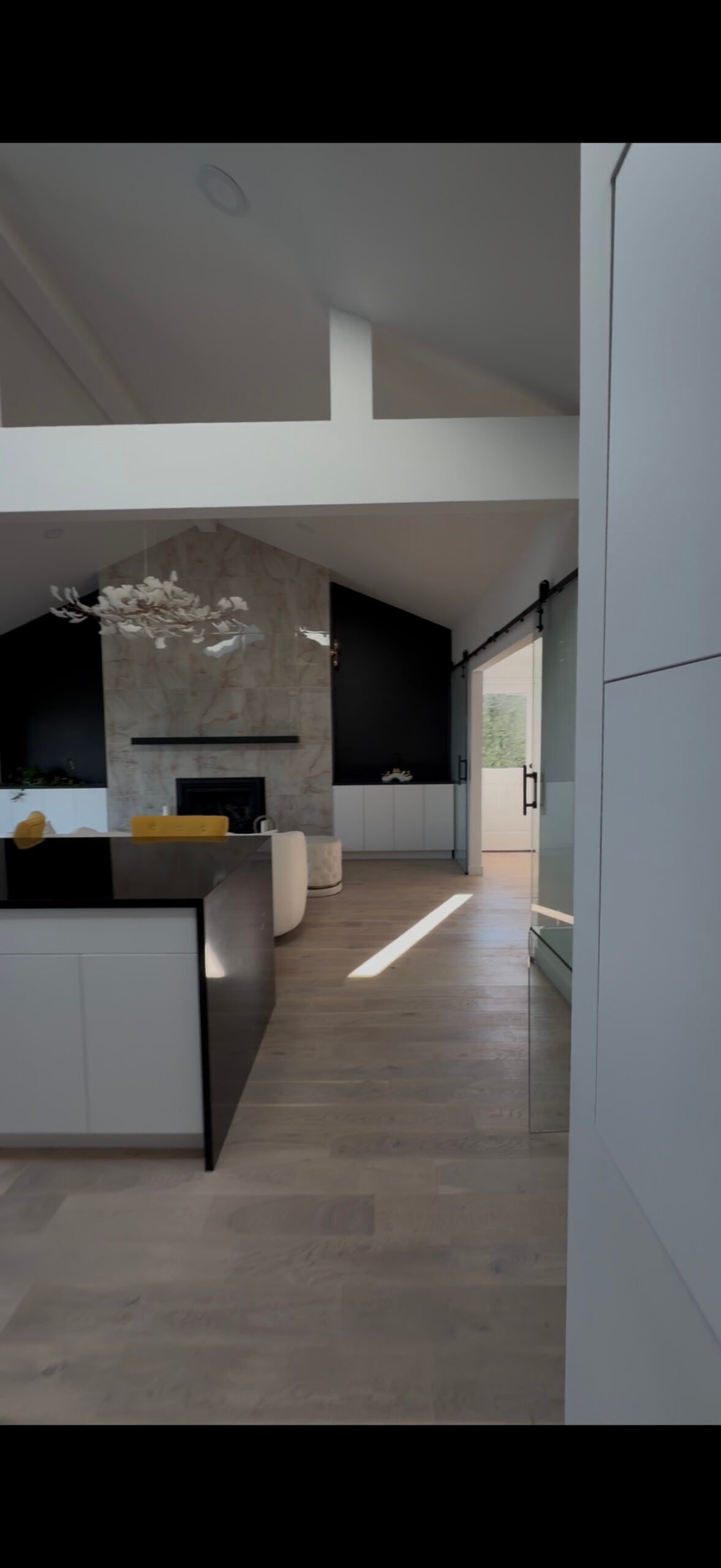 Modern living room with high ceilings, marble fireplace, and large windows filling the space with sunlight.