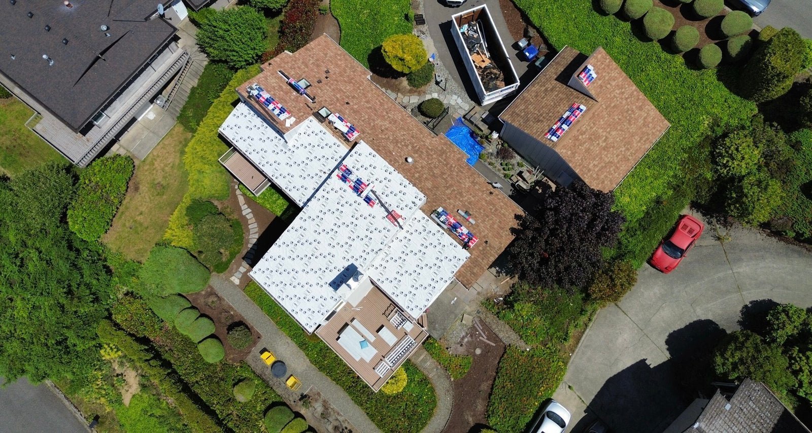 Aerial view of roofers installing roofing materials, with tools and supplies arranged across the rooftop.