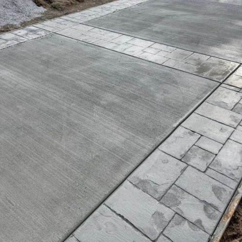 A freshly poured driveway shows stamped decorative concrete borders and smooth, elegant center sections.