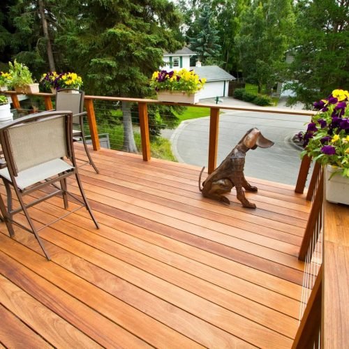 “Construction workers building an outdoor deck for a residential property. The site shows wooden or composite decking materials being installed, with tools, scaffolding, and safety equipment visible, highlighting the step-by-step deck construction process.”