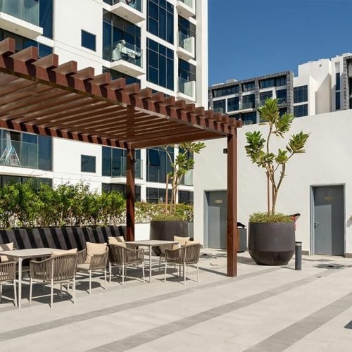A spacious outdoor patio area at the Marina Towers in Dubai, featuring comfortable seating arrangements, lush greenery, and panoramic views of the surrounding cityscape. The space is designed for relaxation and social gatherings, offering a serene environment amidst the bustling city.
